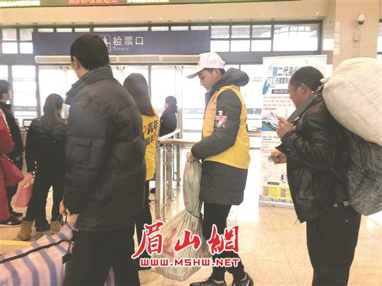 在彭山北站，青年志愿者帮农民工拿行李。.jpg