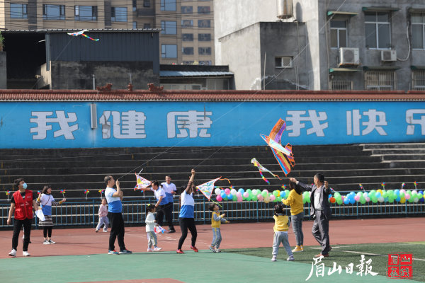 一群幼儿与家长正在放飞风筝。