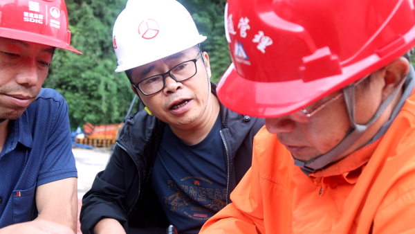 邓庆（中）在项目现场讨论施工要点。