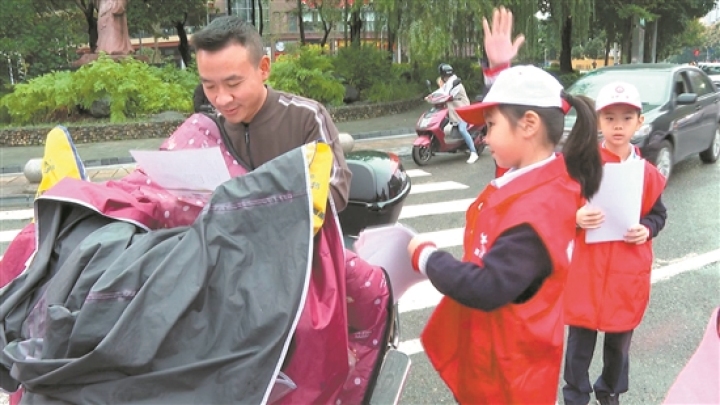 小小志愿者为过往行人和车辆发放文明出行宣传单。.jpg