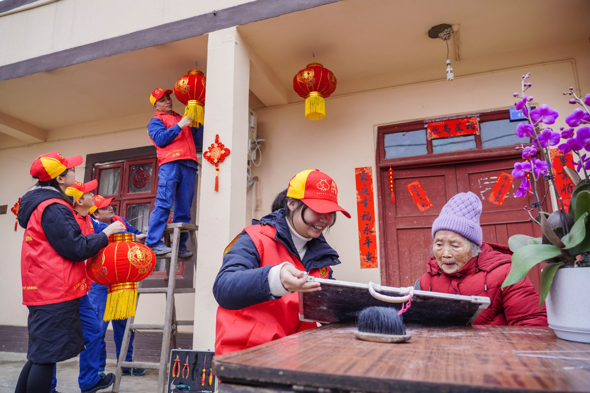 开展新时代文明实践活动，志愿者为老人贴对联