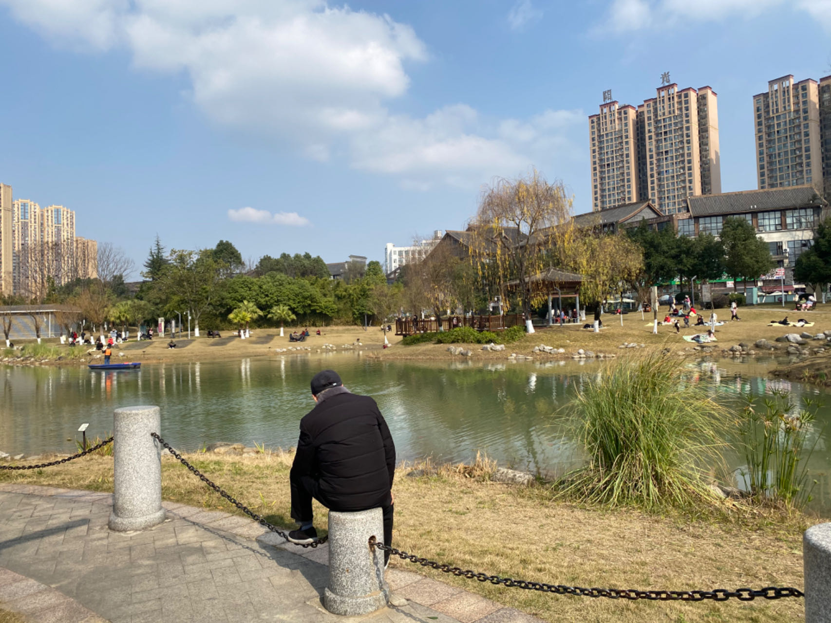 游客坐在石墩上晒太阳，一只脚肆意地踩在铁链上